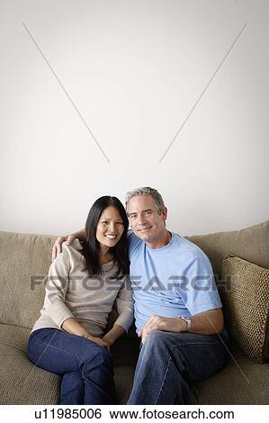 Couple in close embrace sitting on sofa View Large Photo Image Stock Photograph - Couple in close embrace sitting on sofa. Fotosearch