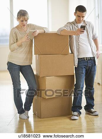 Stock Image - Couple leaning on cardboard boxes during relocation. Fotosearch