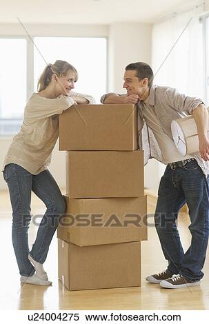 Stock Photography - Couple leaning on cardboard boxes during relocation. Fotosearch