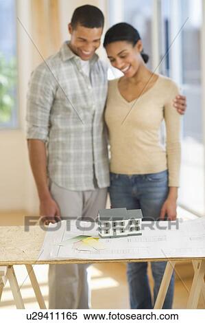 Couple looking at house blueprints and toy model View Large Photo Image Stock Photography - Couple looking at house blueprints and toy model. Fotosearch