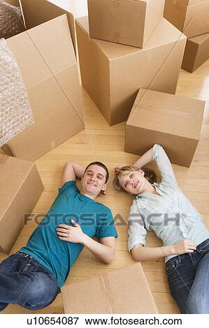 Couple lying among cardboard boxes during relocation View Large Photo Image Stock Photo - Couple lying among cardboard boxes during relocation. Fotosearch