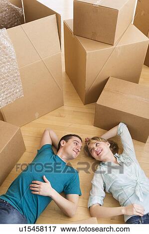 Stock Photo - Couple lying among cardboard boxes during relocation. Fotosearch