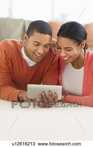 Couple lying on floor reading e-book View Large Photo Image Stock Image - Couple lying on floor reading e-book. Fotosearch