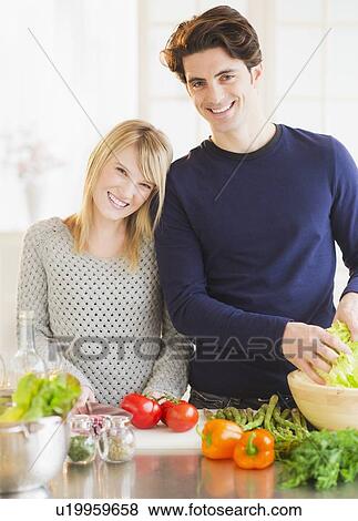 Stock Photo - Couple preparing food in kitchen. Fotosearch