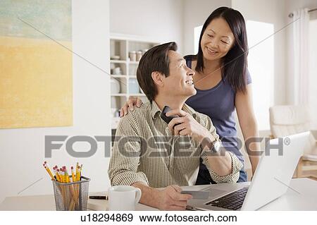 Stock Photo - Couple shopping online from home. Fotosearch