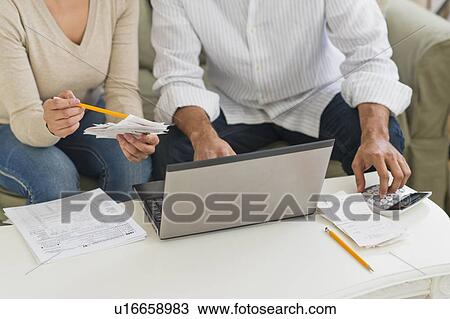 Couple using laptop and calculator View Large Photo Image Stock Image - Couple using laptop and calculator. Fotosearch
