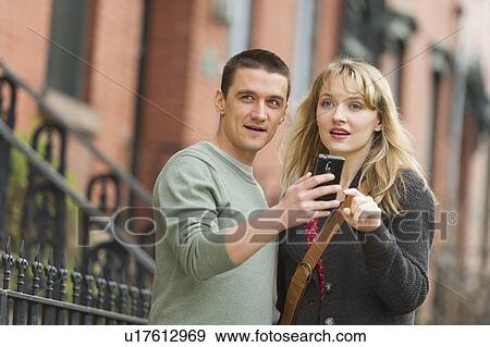 Stock Photo - Couple using smart phone on street. Fotosearch