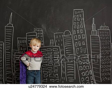 Picture - Cute toddler boy (2-3) standing against blackboard with city skyline drawn on it. Fotosearch