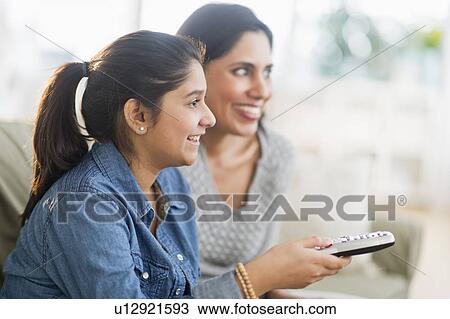 Stock Image - Daughter (12-13) and mother watching tv. Fotosearch