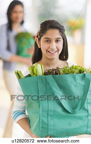 Daughter (12-13) holding bag of fresh vegetables, mother in background View Large Photo Image Stock Image - Daughter (12-13) holding bag of fresh vegetables, mother in background. Fotosearch