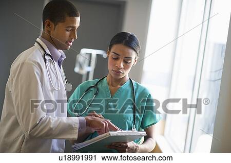 Doctor and nurse talking in hallway View Large Photo Image Stock Image - Doctor and nurse talking in hallway. Fotosearch