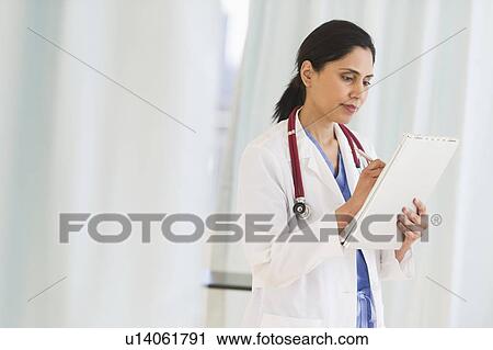 Stock Image - Doctor filling medical document. Fotosearch
