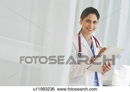 Stock Photograph - Doctor filling medical document. Fotosearch