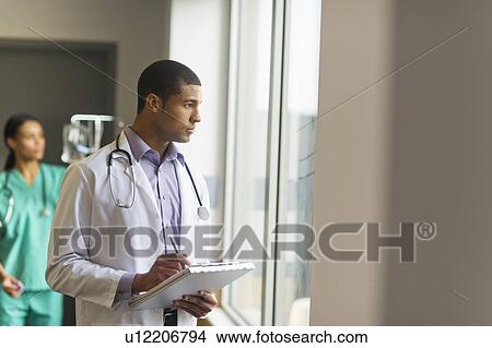 Picture - Doctor looking through window. Fotosearch