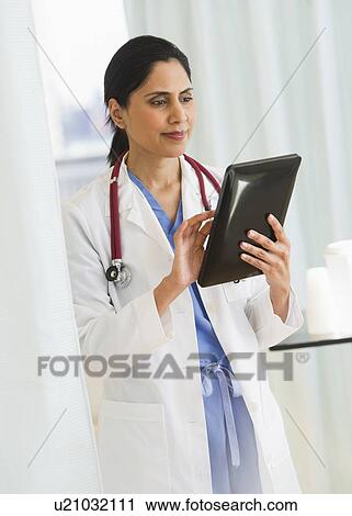 Stock Image - Doctor working on digital tablet. Fotosearch