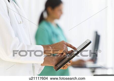 Doctors working on digital tablet and computer View Large Photo Image Picture - Doctors working on digital tablet and computer. Fotosearch