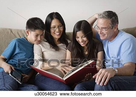 Stock Image - Family watching photo album together. Fotosearch