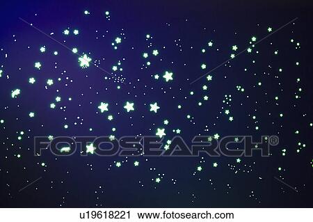 Stock Image - Fluorescent stars on blue background, studio shot. Fotosearch
