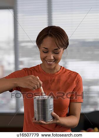 Front view of woman holding paint can and paintbrush View Large Photo Image Stock Photo - Front view of woman holding paint can and paintbrush. Fotosearch