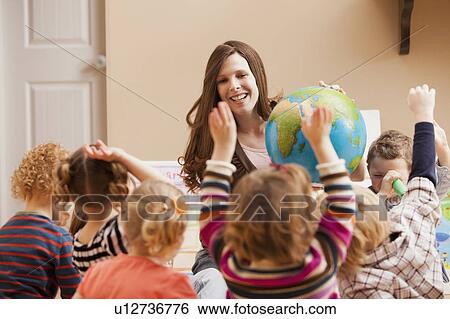 Stock Photograph - Geography teacher with children (2-3, 4-5) raising hands. Fotosearch