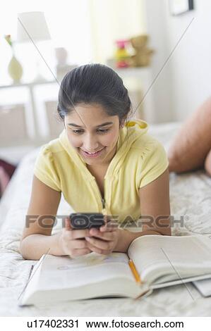 Girl (12-13) lying on bed and texting View Large Photo Image Stock Image - Girl (12-13) lying on bed and texting. Fotosearch