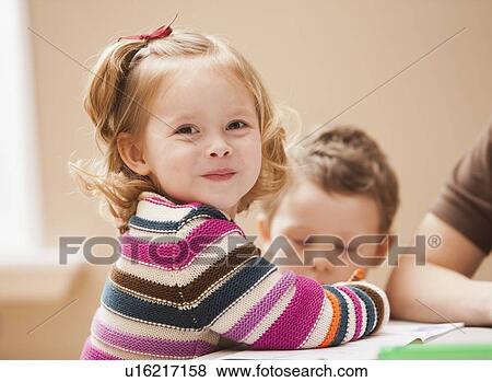 Stock Photo - Girl (2-3) looking at camera during art lesson in kindergarten. Fotosearch