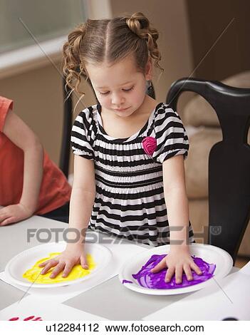 Girl (4-5) holding her hands on plates with paint View Large Photo Image Stock Image - Girl (4-5) holding her hands on plates with paint. Fotosearch