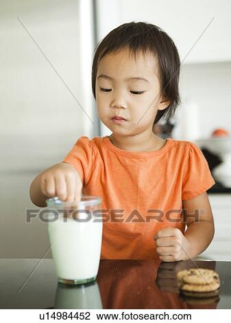 Girl dipping cookie into milk glass (2-3) View Large Photo Image Stock Image - Girl dipping cookie into milk glass (2-3). Fotosearch