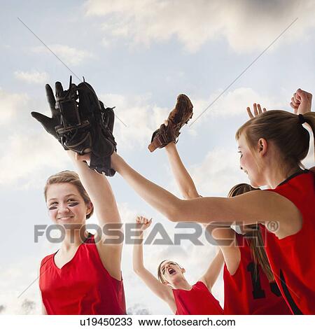 Stock Image - Girls (12-13) celebrating during playing softball. Fotosearch