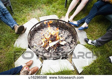 Stock Photograph - Group of friends sitting by bonfire. Fotosearch