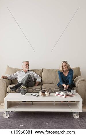 Stock Image - Happy senior couple sitting on sofa. Fotosearch