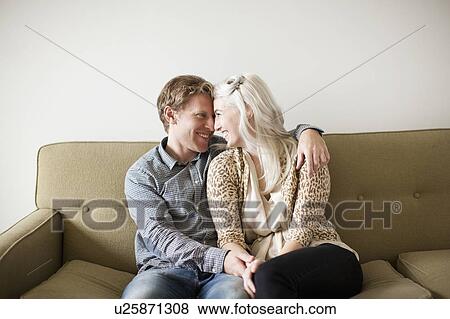 Happy young couple embracing on sofa View Large Photo Image Stock Photo - Happy young couple embracing on sofa. Fotosearch