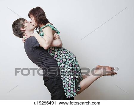 Happy young couple kissing in studio View Large Photo Image Stock Image - Happy young couple kissing in studio. Fotosearch