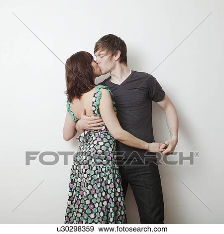 Happy young couple kissing in studio View Large Photo Image Stock Photo - Happy young couple kissing in studio. Fotosearch