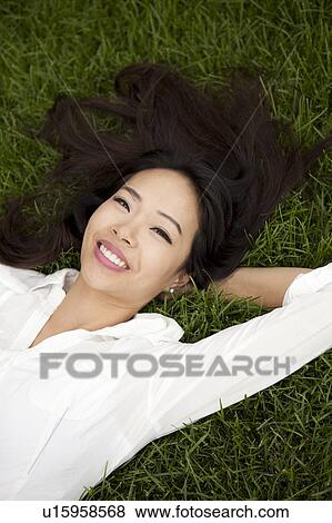 Stock Photo - High angle view of smiling woman lying on lawn. Fotosearch