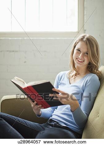 Stock Photo - Indoor portrait of young attractive woman sitting with book. Fotosearch