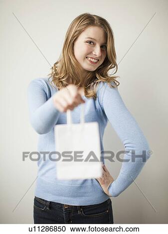 Indoor portrait young happy woman showing white present bag View Large Photo Image Stock Image - Indoor portrait young happy woman showing white present bag. Fotosearch
