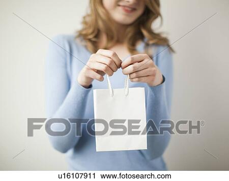 Indoor portrait young happy woman showing white present bag View Large Photo Image Stock Image - Indoor portrait young happy woman showing white present bag. Fotosearch