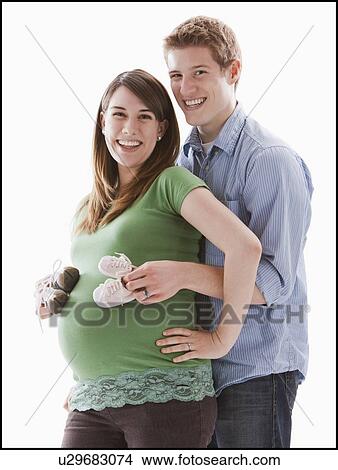 Picture - Man embracing pregnant woman, studio shot. Fotosearch