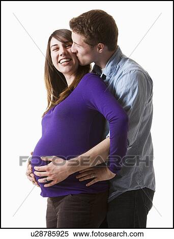 Stock Photography - Man embracing pregnant woman, studio shot. Fotosearch