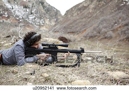 Stock Image - Man lying on front with weapon. Fotosearch