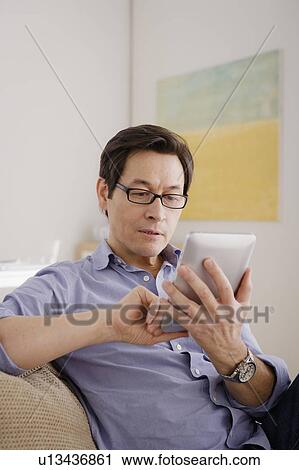 Stock Image - Man reading e-book at home. Fotosearch