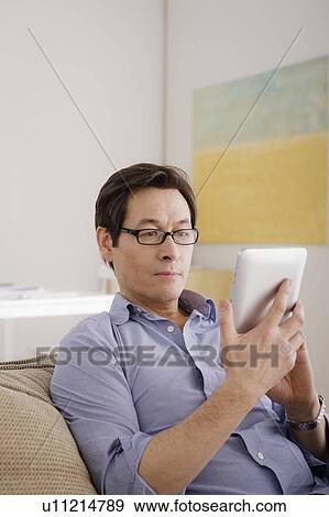 Man reading e-book at home View Large Photo Image Stock Photo - Man reading e-book at home. Fotosearch