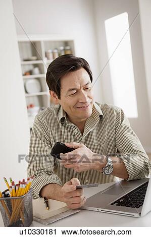 Stock Image - Man shopping online from home. Fotosearch