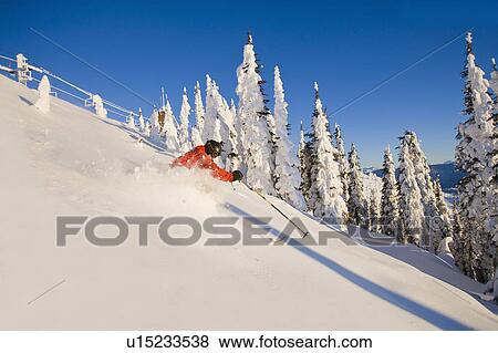 Stock Photo - Man skiing powder in mountain scenery. Fotosearch