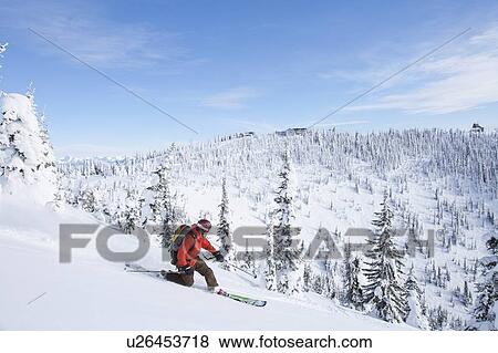 Stock Photo - Man skiing powder in mountain scenery. Fotosearch