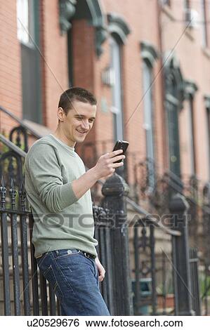 Stock Photograph - Man using smart phone on street. Fotosearch