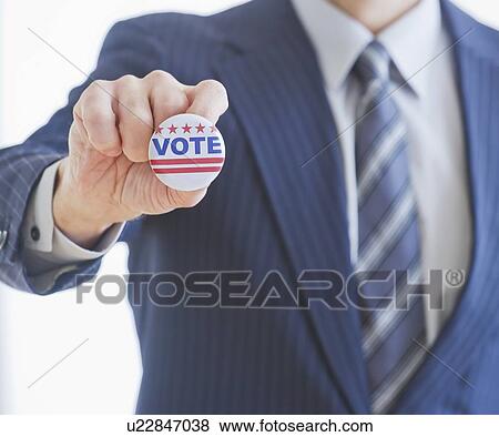 Man wearing suit holding vote pin View Large Photo Image Stock Photo - Man wearing suit holding vote pin. Fotosearch