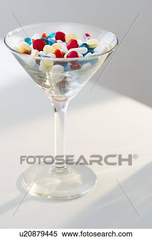 Stock Photography - Martini glass filled with pills, studio shot. Fotosearch