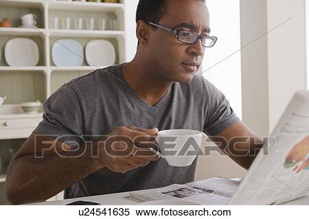 Stock Photography - Mature man drinking coffee and reading newspaper. Fotosearch
